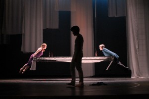 Antigone (Lauren Rekhelman) and Kreon (Grace Starr) have a conflict as Nick (Matthew Schetina) travels across the stage.