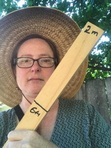 Photo of Janet wearing a sunhat and holding a tick marked "6ft" and "2m"